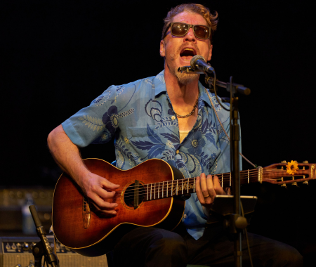 A man is playing a guitar and singing into a microphone
